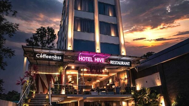 Et hotel med et skilt, der viser 'HOTEL HIVE', og et 'COFFEENESS' skilt nedenunder.