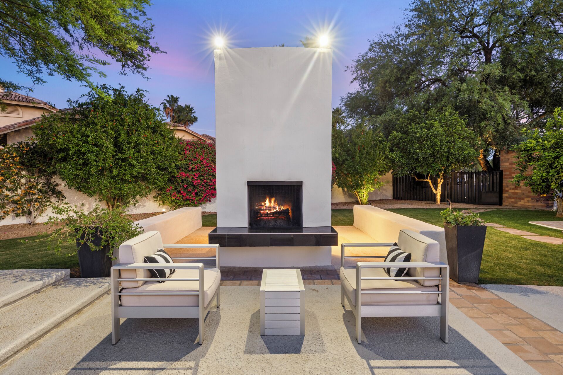 An outdoor patio with a fireplace, two sofas, and a coffee table.