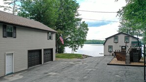 A two-story house with a garage, a basketball hoop, and a dock extending into a lake. - Peaceful Point Waterfront Dogs Welcome, Near Acadia National Park & Bar Harbor (Eddington)