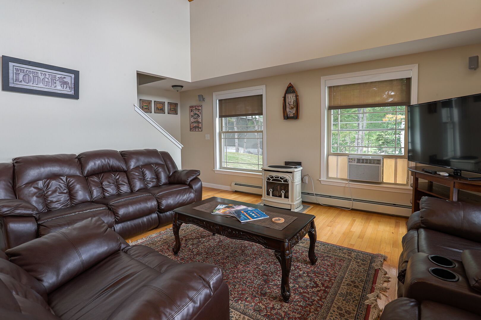A living room with a brown leather sofa, a coffee table with magazines, a fireplace, and a television.