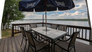 A deck with a table and chairs, overlooking a lake. - Peaceful Point Waterfront Dogs Welcome, Near Acadia National Park & Bar Harbor (Eddington)