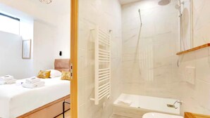 Une salle de bain moderne avec une douche, des toilettes et une baignoire blanche.