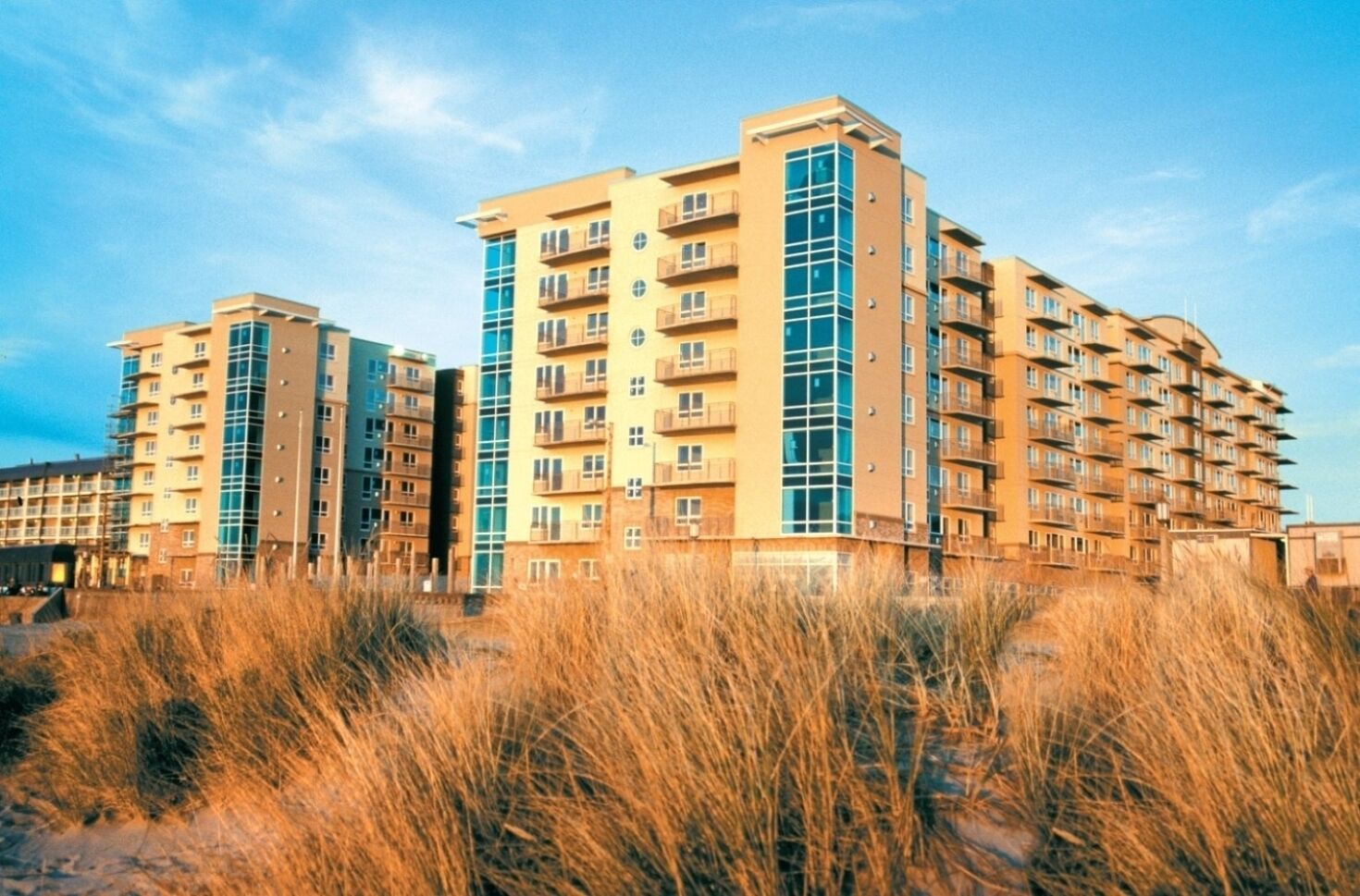 A multi-story residential building with balconies, a flat roof, and a clear sky.
