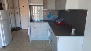 Eine kompakte Küche mit Mikrowelle, Spüle und kleinem Kühlschrank.
