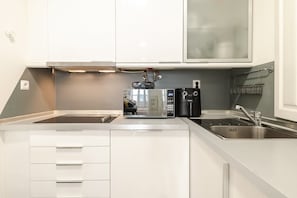 Eine moderne Küche mit weißen Schränken, einer eingebauten Mikrowelle, einer Kaffeemaschine und einem Edelstahl-Spülbecken.