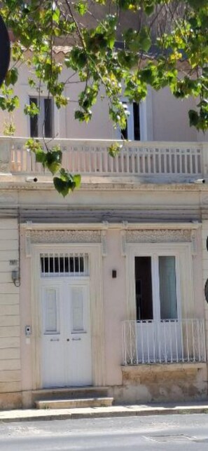 A building with a white door, a small balcony with a railing, and a window above the door. - Elegant Detached House in the City Center (Avola)