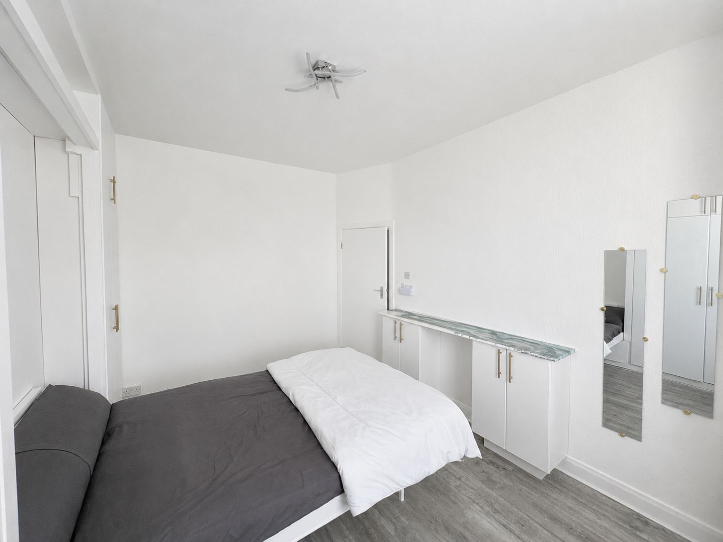 A bedroom with a bed, a wardrobe, a mirror, and a ceiling fan.