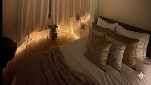 Ein Schlafzimmer mit Bett, Vorhängen, Deckenventilator und Heizkörper.