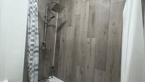 Ein modernes Badezimmer mit einer freistehenden Badewanne, einer Dusche mit Regendusche und einem karierten Duschvorhang.
