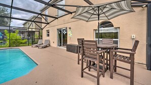 Ein Außenpoolbereich mit überdachter Terrasse, Liegestühlen und einem Tisch mit Stühlen.