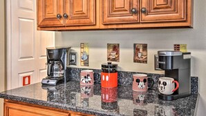 Eine Küche mit Holzschränken, einer Kaffeemaschine und Mickey Mouse-Tassen auf der Arbeitsfläche.
