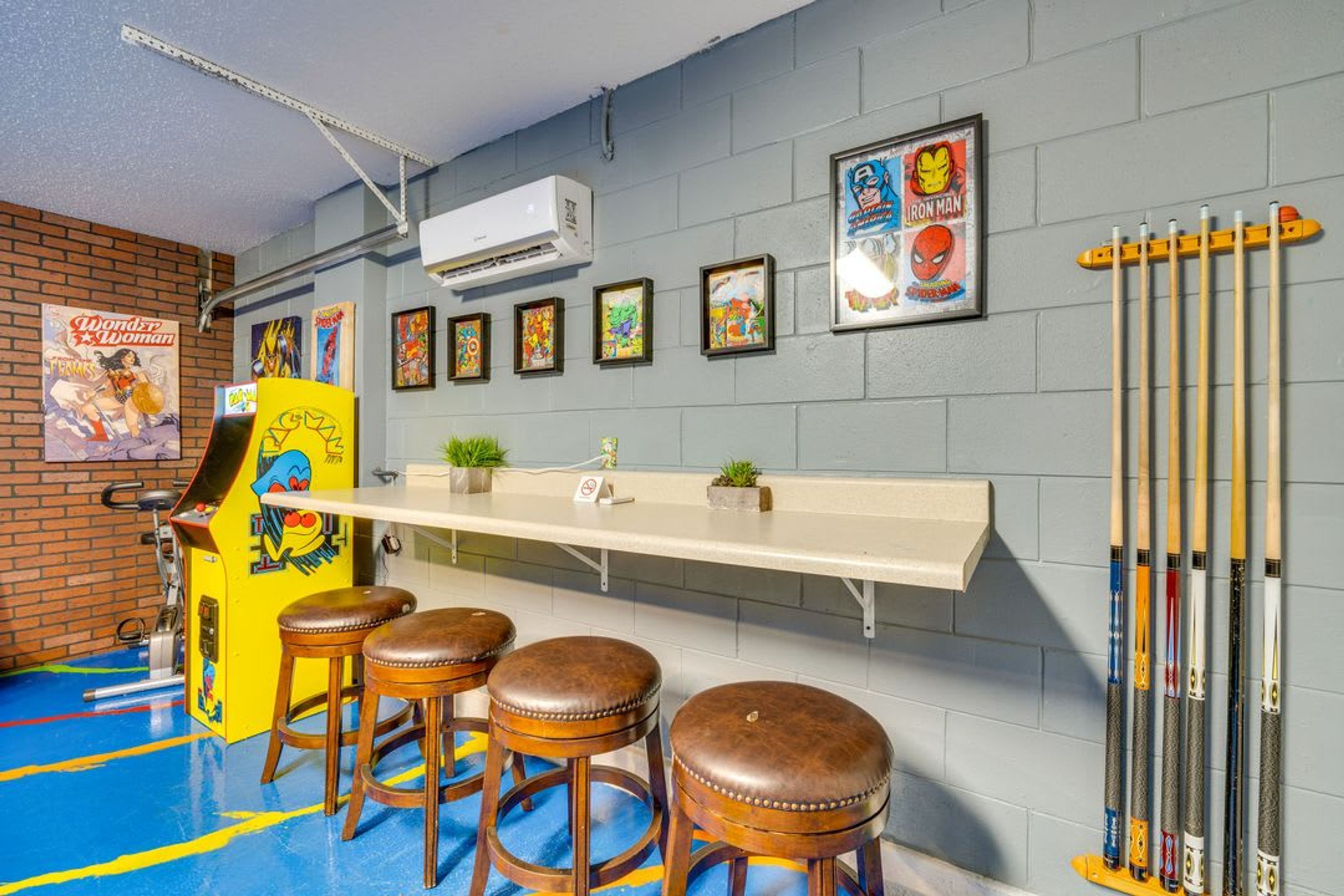 Un espace bar avec des tabourets, un comptoir et des affiches encadrées accrochées au mur.