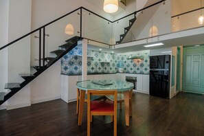 A modern kitchen with patterned backsplash, a dining table with chairs, and a staircase with glass railings. - JIMDO HOME 38 - THE BEST LOCATION (Thành phố Hồ Chí Minh)