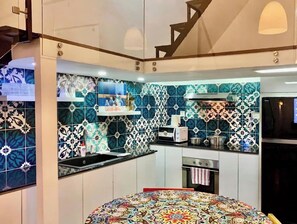 A kitchen with patterned tiles, a stove, a microwave, and a sink. - JIMDO HOME 38 - THE BEST LOCATION (Thành phố Hồ Chí Minh)