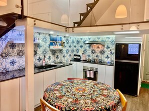 Une cuisine compacte avec une table de salle à manger ronde, un four encastré et un réfrigérateur.