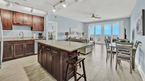 A spacious kitchen with a large island, wooden cabinets, and a dining area with a table and chairs. - Blue Skies and Gulf Breezes! Enjoy Blue Serenity at LTW Nice Gulf View balcony (Panama City Beach)