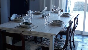 Een eetkamer met een lange tafel voor zes personen, omringd door stoelen.