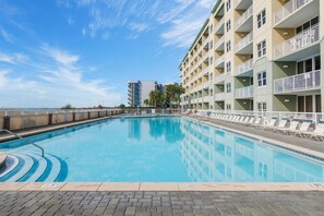 A swimming pool with a clear blue water surface, surrounded by a brick walkway. - Waters Edge #501 (Fort Walton Beach)