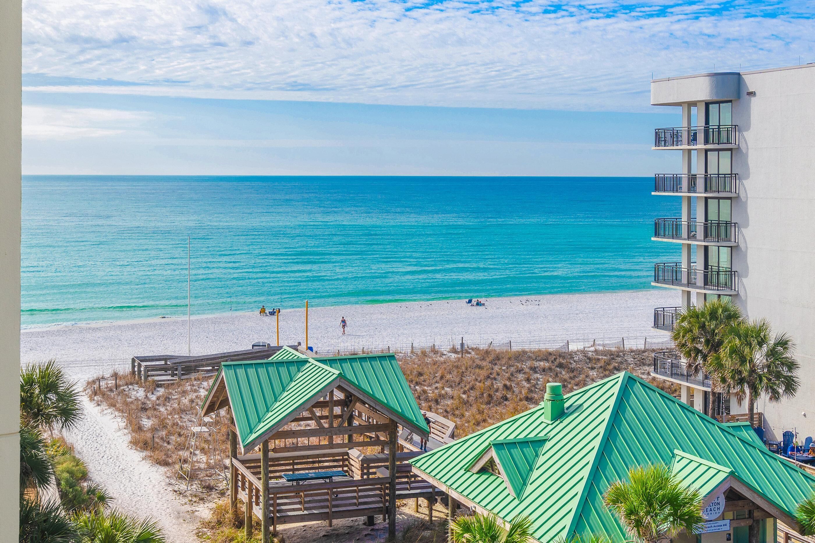 A beach view with a wooden structure and a modern building with balconies.