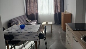 Ein kompakter Wohnbereich mit Sofa, Esstisch und Küchenzeile.