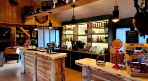 Un coin bar au style rustique, avec des meubles en bois, des luminaires suspendus et des étagères remplies de bouteilles.