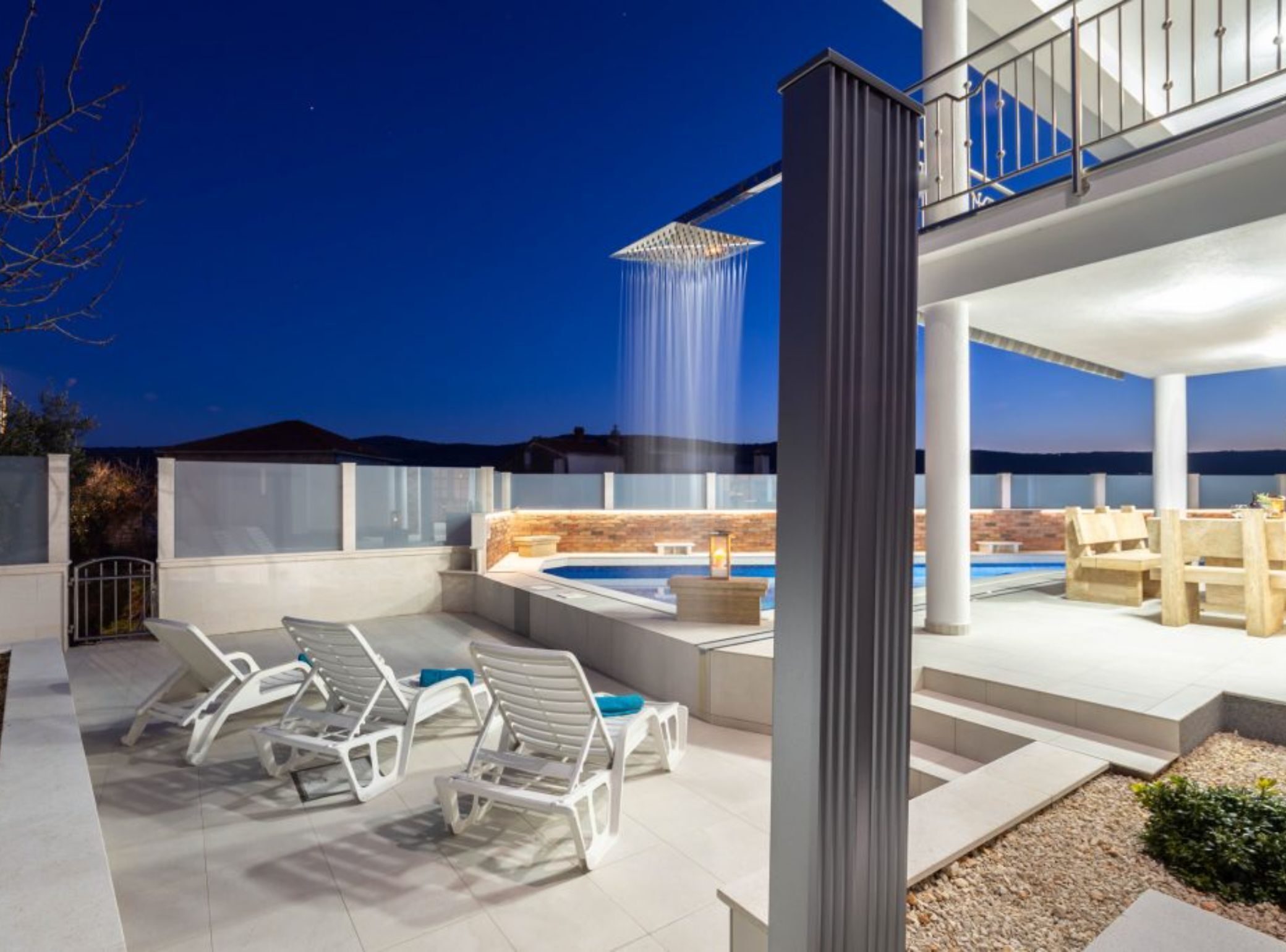 A rooftop patio with a hot tub, lounge chairs, and a waterfall feature.