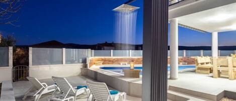 A rooftop patio with a hot tub, lounge chairs, and a waterfall feature.