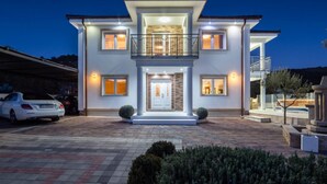 Une maison à deux étages avec un balcon, une allée et une pelouse bien entretenue.