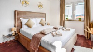 Une chambre à coucher avec un grand lit, une table de chevet, une fenêtre avec des rideaux et une vue sur l’extérieur.