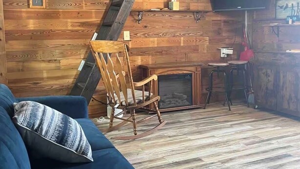 Un intérieur rustique avec des éléments en bois, un canapé bleu, un fauteuil à bascule et une cheminée.