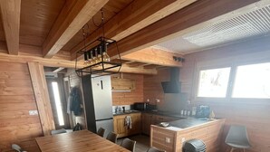 A modern kitchen with wooden cabinetry, a large wooden dining table, and black chairs.