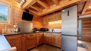 A wooden kitchen with a refrigerator, microwave, and toaster.