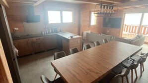 A spacious kitchen with wooden cabinets, a large dining table with chairs, and a view of the outdoors.