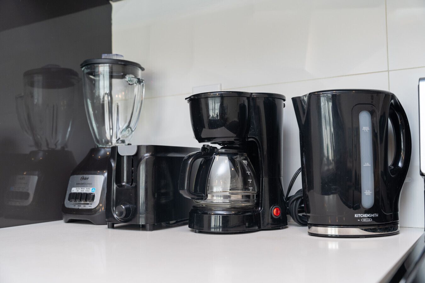 A kitchen counter with a coffee maker, a blender, and a kettle.
