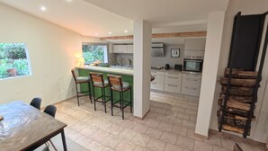 A modern kitchen with a bar area, a dining table, and chairs. - Les Salines de Réals - In the heart of the garrigue, ideal for a quiet interlude (Cessenon sur Orb)