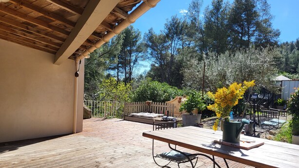 A wooden deck with a picnic table, surrounded by a white picket fence and potted plants. - Les Salines de Réals - In the heart of the garrigue, ideal for a quiet interlude (Cessenon sur Orb)
