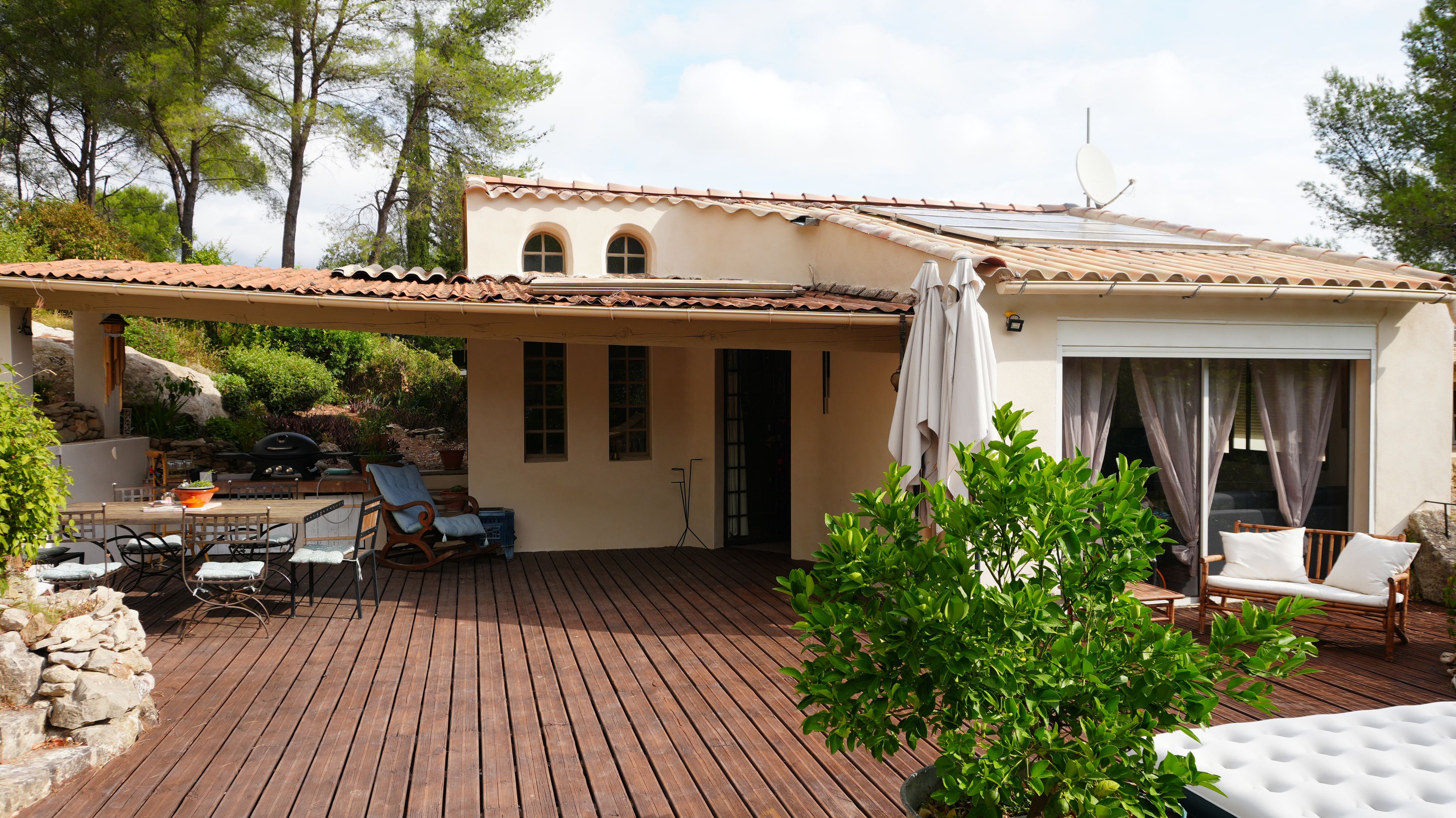 A patio with wooden flooring, outdoor furniture, and a covered area with a pergola.