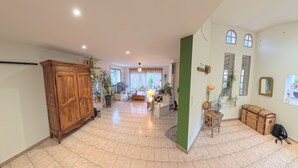 A spacious living area with a wooden cabinet, a sofa, a coffee table, and a TV. There are potted plants and a lamp. - Les Salines de Réals - In the heart of the garrigue, ideal for a quiet interlude (Cessenon sur Orb)