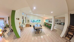 A spacious kitchen with modern appliances, a dining area with a large table and chairs, and a view of a garden through a window. - Les Salines de Réals - In the heart of the garrigue, ideal for a quiet interlude (Cessenon sur Orb)