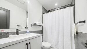 A modern bathroom with a white sink, a toilet, and a shower curtain. - Five-Star Comfort in a luxury Home (Brampton)