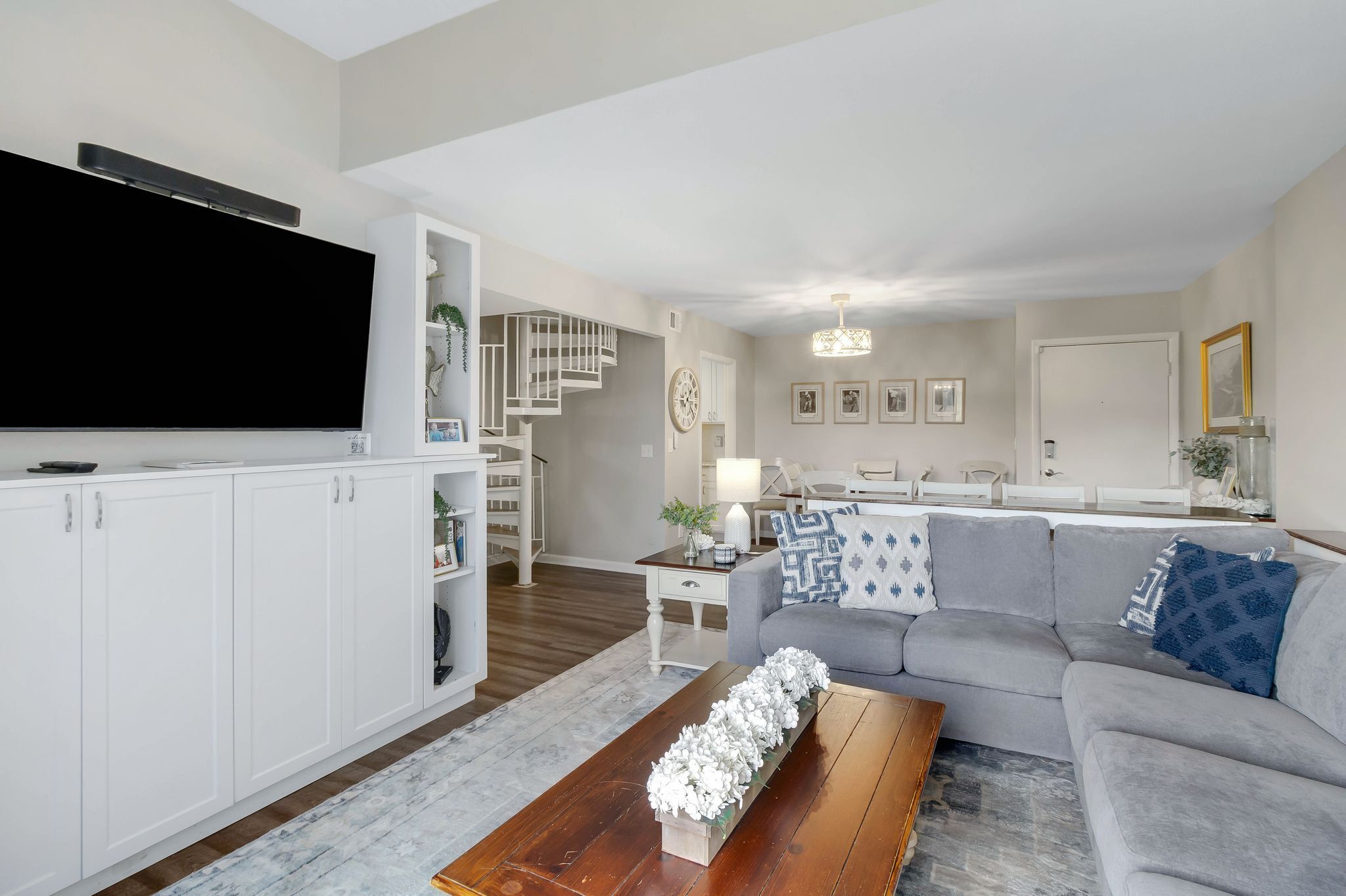 A modern living room with a flat-screen TV, a grey sofa, and a wooden coffee table.