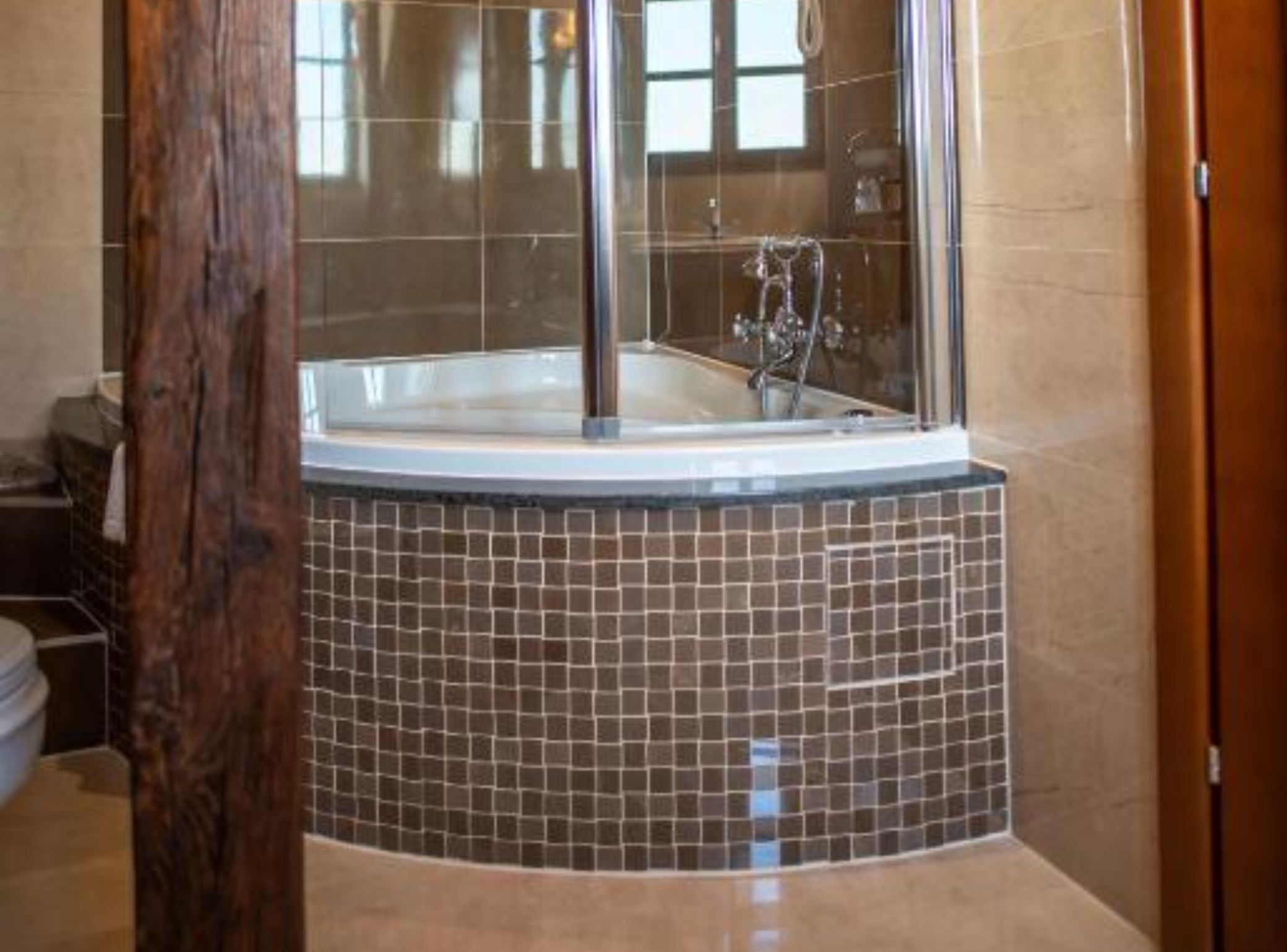 A bathroom with a large bathtub, tiled walls, and a wooden column.