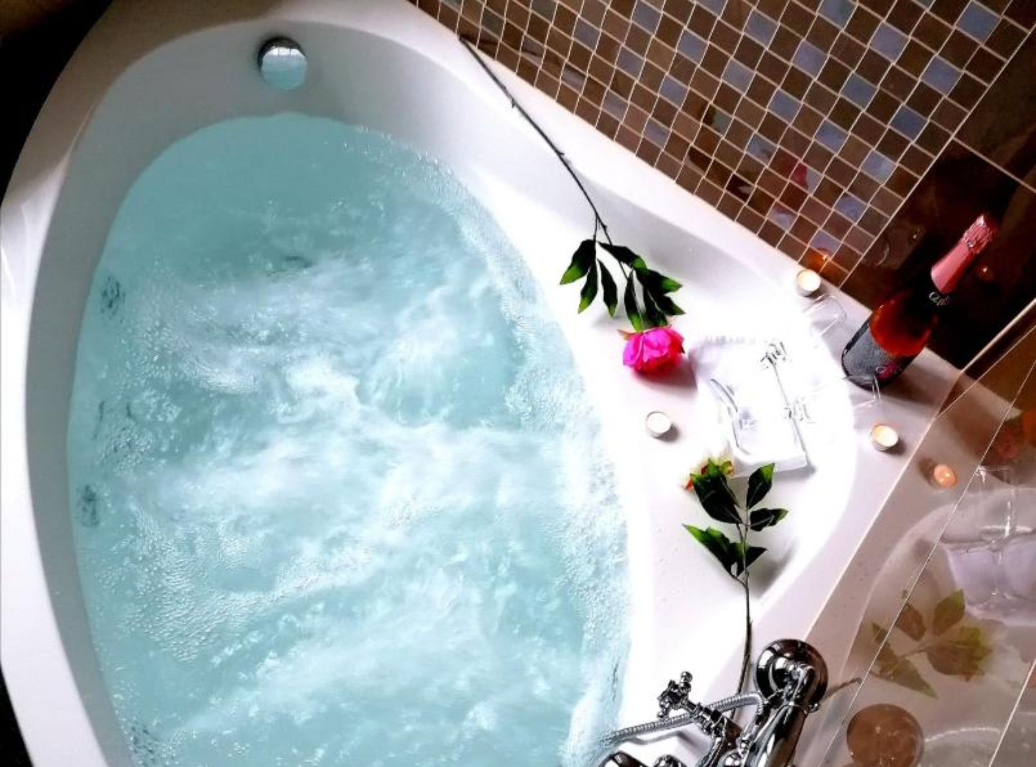 A bathtub with running water, surrounded by decorative elements like flowers and candles.