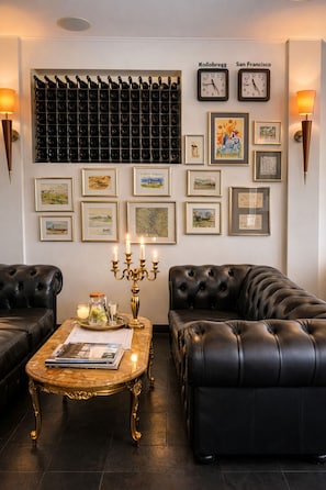 A modern living room with a black leather sofa, a coffee table with a gold base, and a wall-mounted wine rack.
