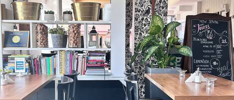 Un espace bar moderne avec des étagères remplies de bouteilles, un menu écrit à la craie et des chaises à rayures.