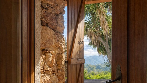 A wooden door with a stone wall, leading to an outdoor deck with a view of mountains and palm trees. - Villa with private pool between sea and mountains, quiet setting (Appietto)