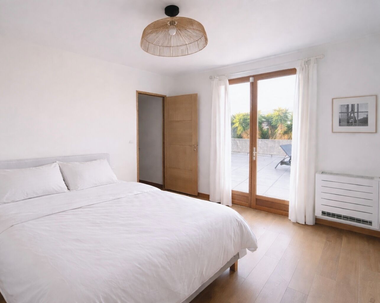 Ein Schlafzimmer mit einem großen Bett, einer Holztür und Blick ins Freie.