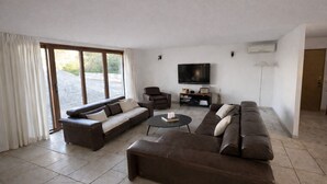 A modern living room with a large sectional sofa, a coffee table, and a flat-screen TV mounted on the wall. - Villa with private pool between sea and mountains, quiet setting (Appietto)