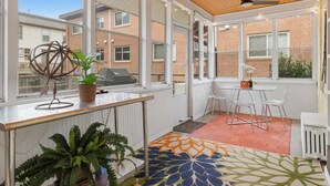 A sunlit room with large windows, a ceiling fan, and a table with chairs. - Charming 4BR Bungalow - Steps to Clarendon METRO (Arlington)