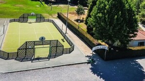Ein Basketballplatz im Freien mit einem Zaun, einem kleinen Gebäude und einem Schild.